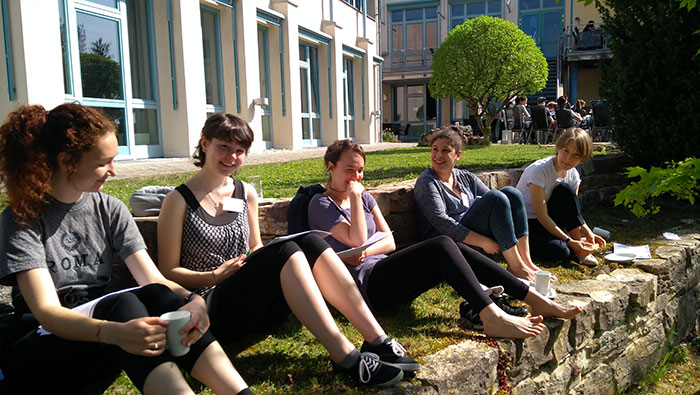 Eine Gruppe junger Frauen sitzen an einem schönen Sommertag im Freien und diskutieren.