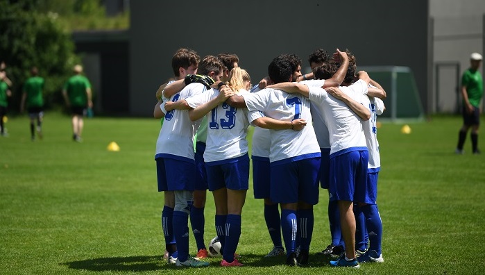  A group of soccer players hug each other on the field.