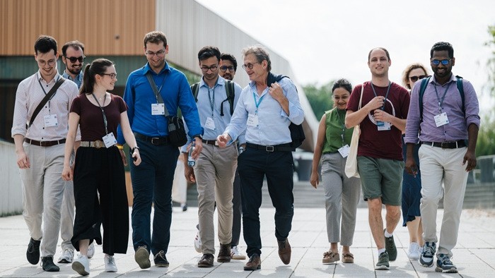 © Torben Nuding An international group of scientists walk together in good spirits across the grounds of a modern research facility.