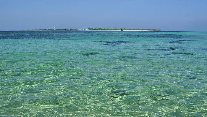 Scenic photo dominated by crystal-clear seawater and, in the distance, a group of islands.