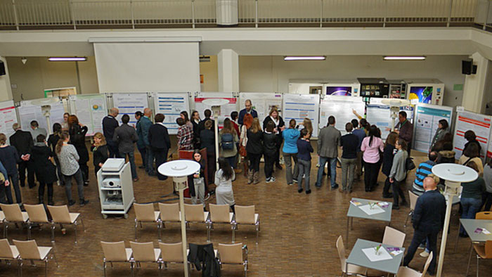 A group of students discusses in front of poster boards.