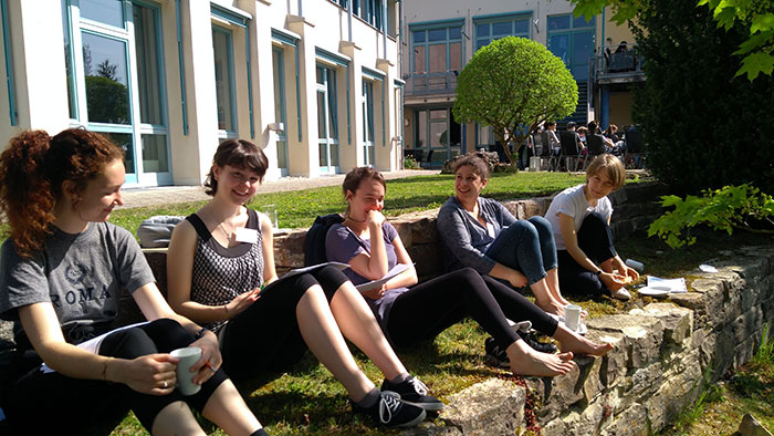 A group of young women sitting outdoors on a beautiful summer day discussing.