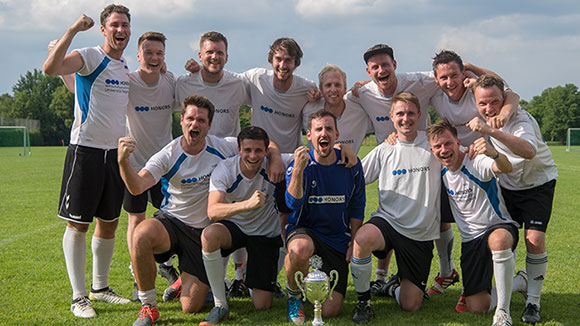 Team photo: footballers celebrate winning a trophy. 