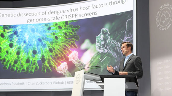 Ein junger Mann hält einen Vortrag über seinen Forschungsansatz zu viralen Infektionen. 