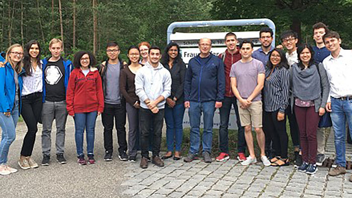 Gruppenbild: Eine Gruppe junger Leute steht an einem Waldweg und lacht in die Kamera