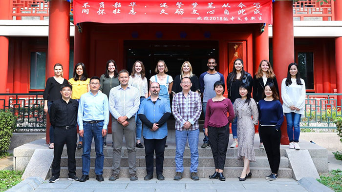 Gruppenbild: Eine Gruppe junger Menschen posiert vor einem chinesisch gestalteten Eingang eines Gebäudes