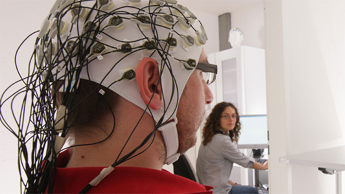 Detailaufnahme einer EEG-Untersuchung bei der Elektroden, die in einer Art Haube eingearbeitet sind, an die Kopfhaut angebracht werden.