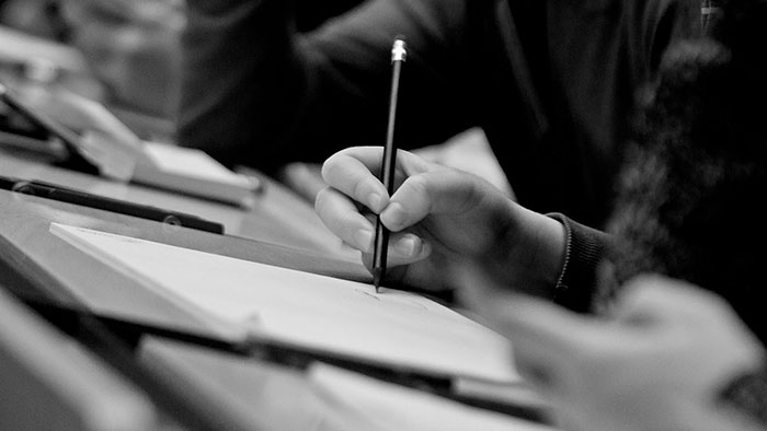 Detail picture: A hand writing on a sheet of paper.