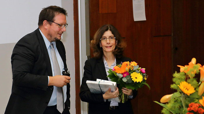 A man thanks a woman with flowers and a book.