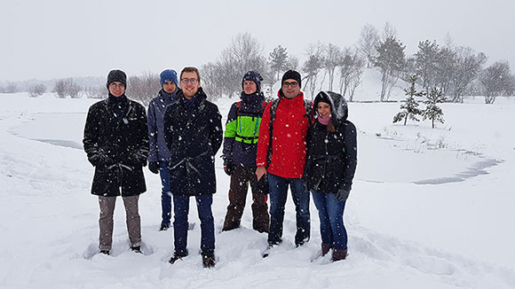 Group photo of six people standing on a snow-covered field.
