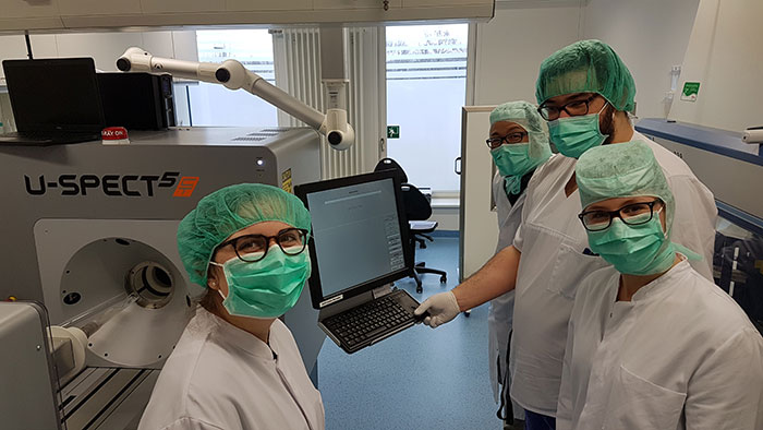 Four people stand in front of a large medical device.