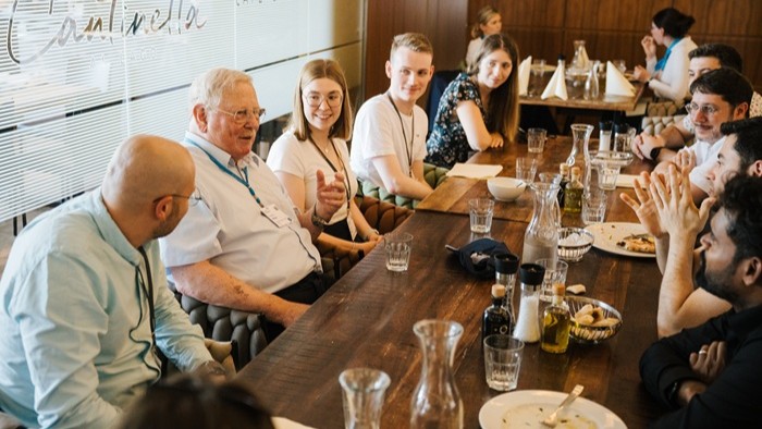 In a relaxed atmosphere, young scientists exchange ideas with a Nobel Prize winner over lunch.