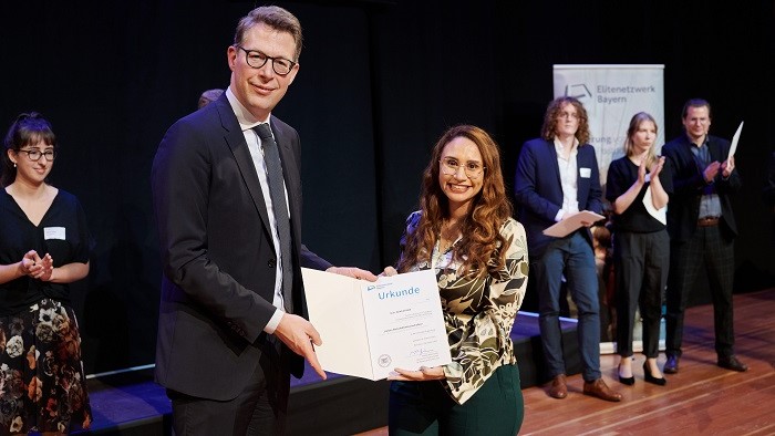 Ein Mann und eine Frau halten ein Zertifikat in der Hand und lächeln in die Kamera.