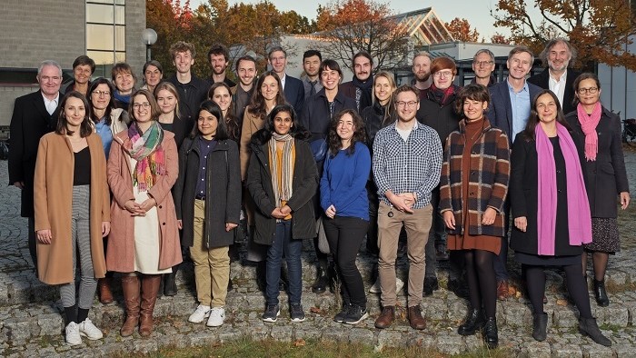 A group of students and their supervisors stand in front of a building.