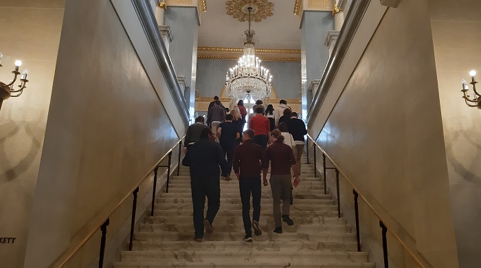 A group of young people is climbing a magnificent and large staircase.