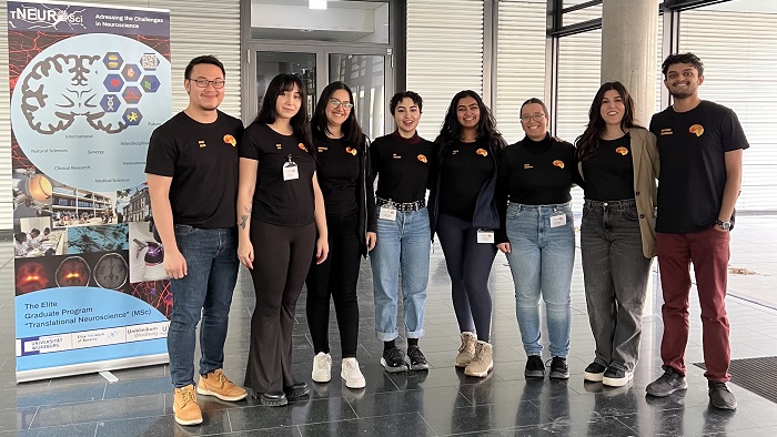 The organization team of the Autumn school stands in the hall of the meeting venue right beside the banner of the master program Translational Neuroscience.