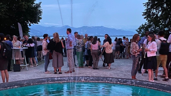 Eine Gruppe von Teilnehmenden steht auf einer Terrasse mit Blick auf den Bodensee