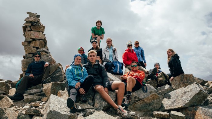 Gruppenbild: Junge Menschen sitzen auf einem Gipfel und schauen in die Ferne.