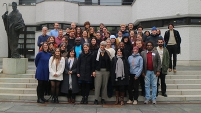 © Kirsten Twelbeck Eine Personengruppe posiert vor einem Gebäude für ein Gruppenfoto.