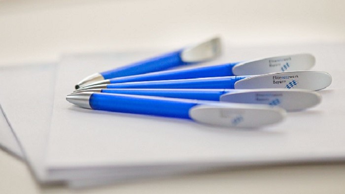 The picture shows pens on top of a stack of paper.