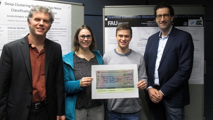 A young woman and a young man stand in front of their research poster with two men.