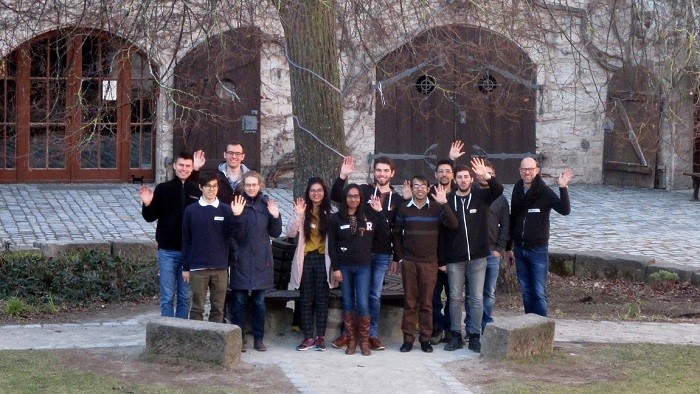 A group of young people waving to the camera in a castle courtyard