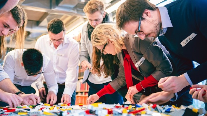 Eine Gruppe junger Menschen baut Lego-Teile zusammen.