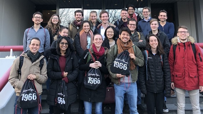 Group picture of young people in front of an entrance to a company building.