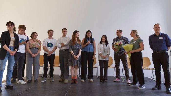 Ein Team aus Studierenden und die Koordinatoren des Studiengangs sind zusammen auf der Bühne der Veranstaltung zu sehen.