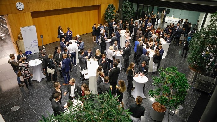 Menschen essen an Tischen in einem großen Foyer.