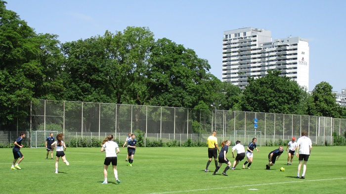 Junge Männer und Frauen beim Fußballspielen auf dem Spielfeld.