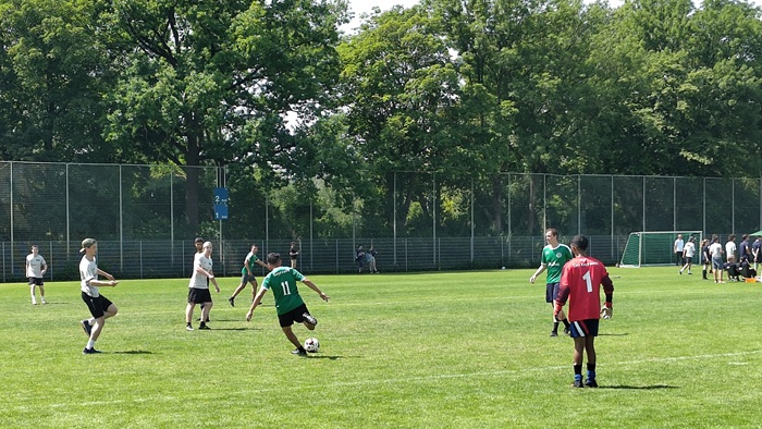 Junge Männer und Frauen beim Fußballspielen auf dem Spielfeld.