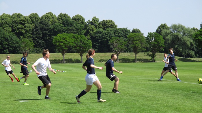 Junge Männer und Frauen beim Fußballspielen auf dem Spielfeld.