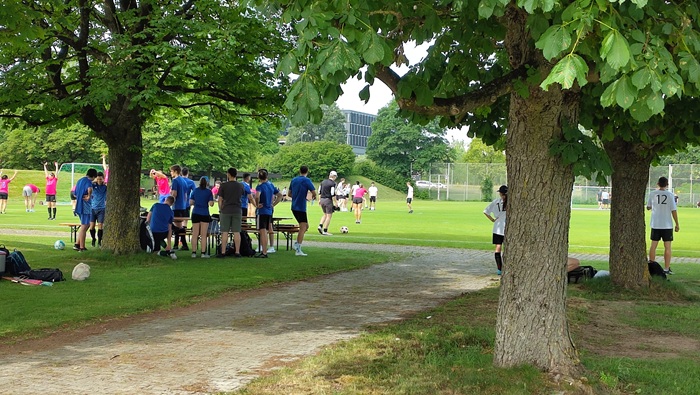 Junge Männer und Frauen beim Fußballspielen auf dem Spielfeld.