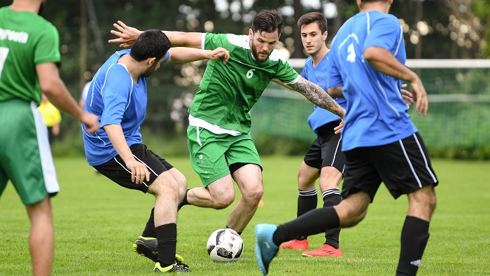 Several players from two different teams fight for the ball on the field.