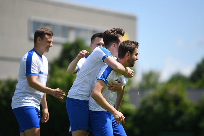 Eine Gruppe junger Männer in Fußballtrikots umarmt sich.