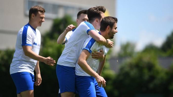 A group of young men in soccer jerseys hug each other.