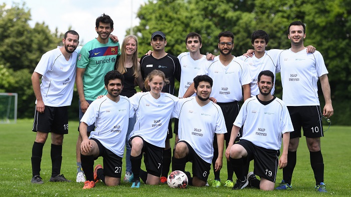 Eine Gruppe junger Männer und Frauen in Fußballtrikots posiert für ein Gruppenbild.