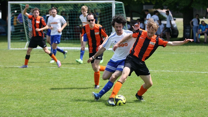 Two players are fighting for the ball while being watched by their teammates.