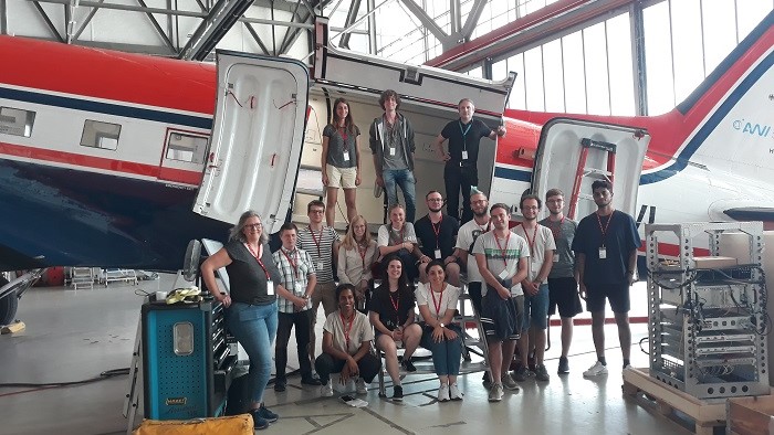 Die Studierenden des Elitestudiengangs Scientific Computing machen ein Gruppenfoto vor einem der AWI-Forschungsflugzeuge im AWI-Hangar.