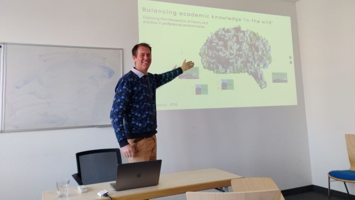 A man is presenting in a room with chairs.