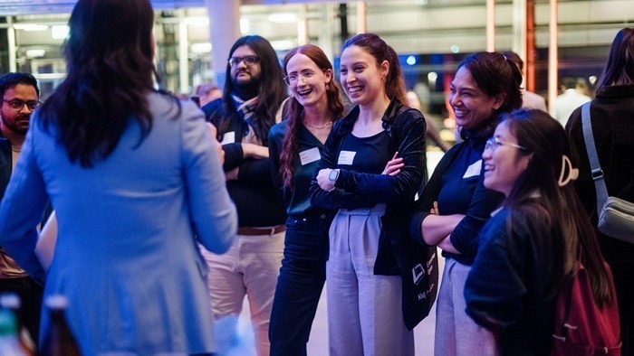 A group of people listen intently to a speaker during an exchange at the network meeting in the foyer.
