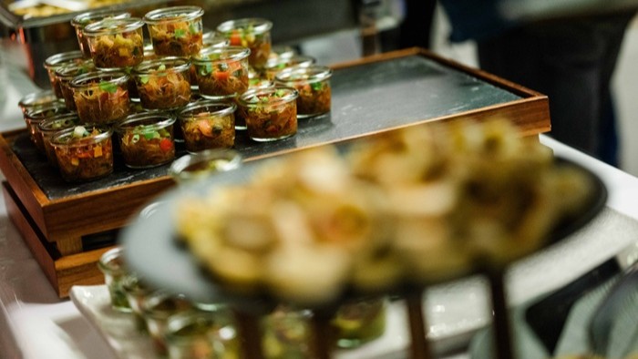 Auf einem Buffet stehen kleine Gläser mit appetitvoll angerichteten Speisen.