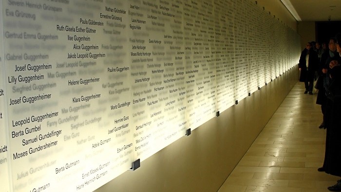 Numerous names on backlit glass panels lining a long hallway.