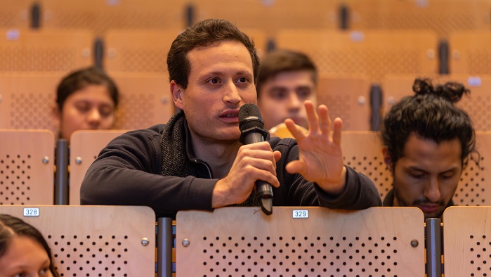 A student sitting in the audience is speaking into a microphone.