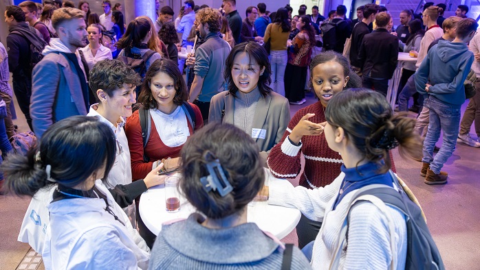 A group of young women are chatting at a bar table.