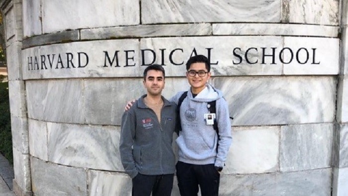 Zwei Doktoranden stehen Schulter an Schulter vor dem Eingang der Harvard Medical School.