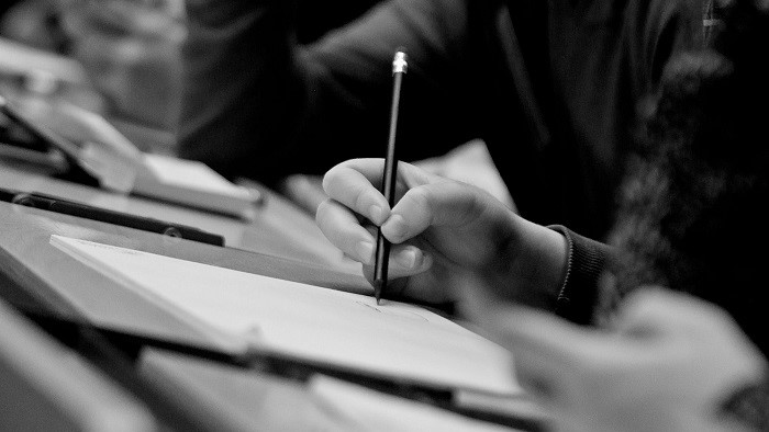 Detail: A hand writes with a pencil in a block.