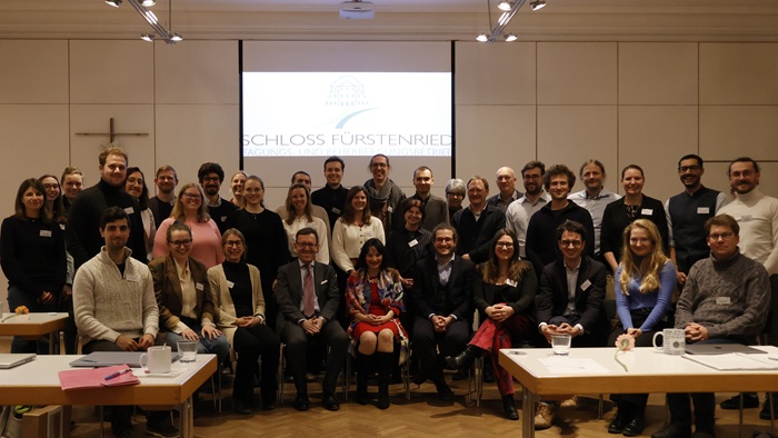 Gruppenfoto der Teilnehmenden der Veranstaltung. Die Menschen stehen oder sitzen in einem Halbkreis vor einem Banner mit der Aufschrift „Schloss Fürstenried“ und lächeln.