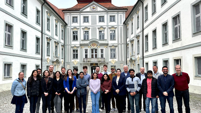 © Dr. Anja Stromeck-Faderl A group of students is standing with professors for a group photo in front of an old and stately building.